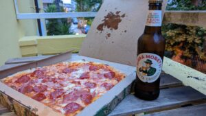 Pizza in a takeout box with a bottle of beer